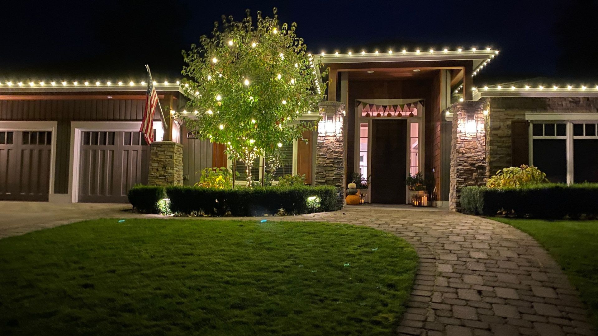 Warm white roofline lights and wreath installed on a Washington home